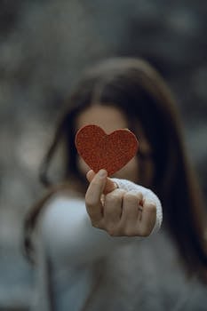Portrait of a woman holding a red heart cut-out, symbolizing love.