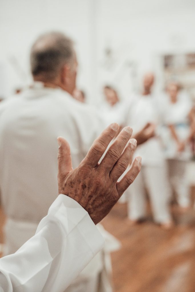 An elderly man raises his hand during a spiritual gathering, evoking a sense of togetherness and spirituality.