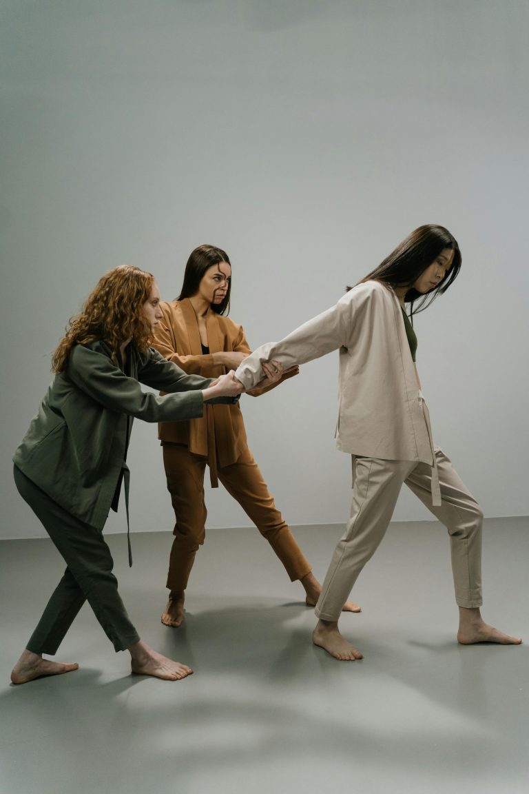 Three diverse women in stylish outfits pose in a modern studio setting, showcasing fashion and unity.